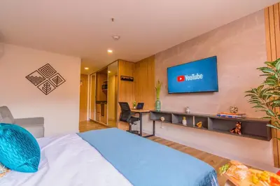 a hotel room with a bed and a tv on the wall at Hermosa Suite CoWork - Gym-WifI El Poblado in Medellín