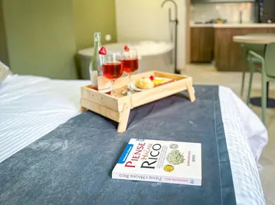 a tray with two glasses of wine and a book on a bed at Loft moderno con bañera Medellín 1-03 in Medellín