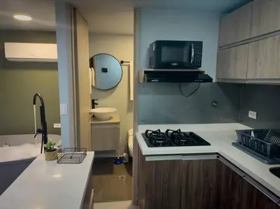 a small kitchen with a stove and a microwave at Loft moderno con bañera Medellín 1-03 in Medellín