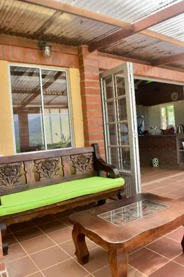 a wooden bench on a porch with a table at Pájaros y Mariposas Casa Campestre in La Rochela