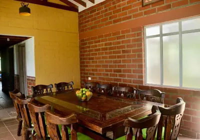 a dining room with a wooden table and chairs at Pájaros y Mariposas Casa Campestre in La Rochela