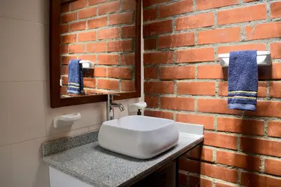 a bathroom with a white sink and a brick wall at Pájaros y Mariposas Casa Campestre in La Rochela