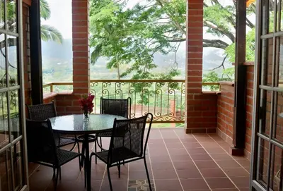 a patio with a table and chairs and a balcony at Pájaros y Mariposas Casa Campestre in La Rochela