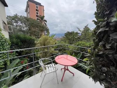 a red table and chair on a balcony with a view at Son de la Loma Apartments in Envigado