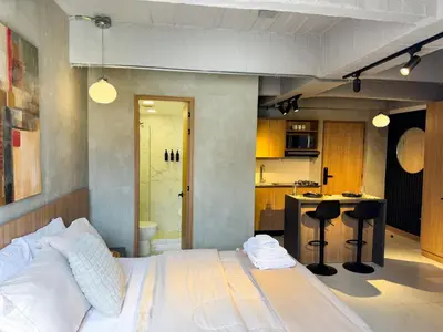 a bedroom with a white bed and a kitchen at Reposso Studio Poblado in Medellín