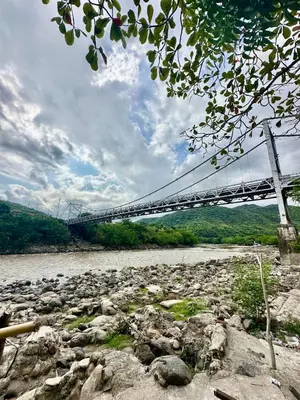 a suspension bridge over a river with rocks at Villa Paulina in Honda