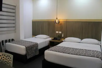 a hotel room with two beds and a table at Hotel Merlott Lleras in Medellín