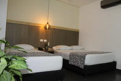 a hotel room with two beds and a potted plant at Hotel Merlott Lleras in Medellín