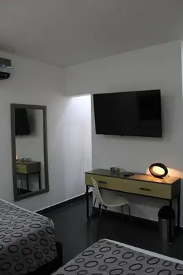a bedroom with a desk and a television on the wall at Hotel Merlott Lleras in Medellín