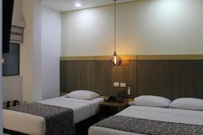 a room with two beds and a pendant light at Hotel Merlott Lleras in Medellín