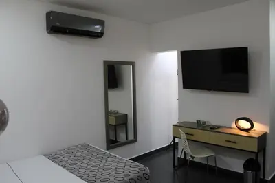 a bedroom with a bed and a desk and a television at Hotel Merlott Lleras in Medellín