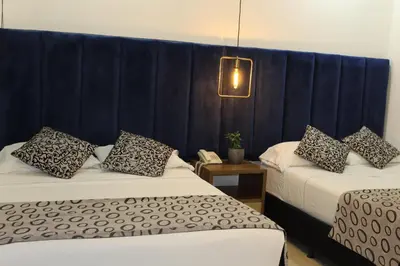 two beds in a room with a blue curtain at Hotel Merlott Lleras in Medellín