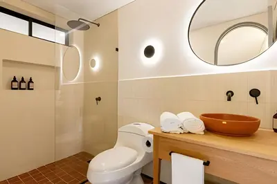 a bathroom with a toilet and a sink and a mirror at Casa Fiora Laureles in Medellín