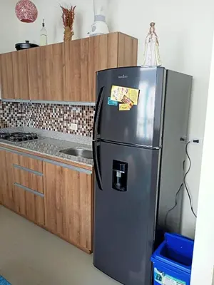 a stainless steel refrigerator in a kitchen with wooden cabinets at Paraíso del sol in San Jerónimo