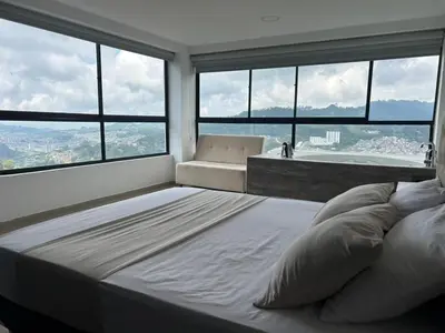 a large bed in a room with large windows at Hotel Golden Hills Manizales in Manizales