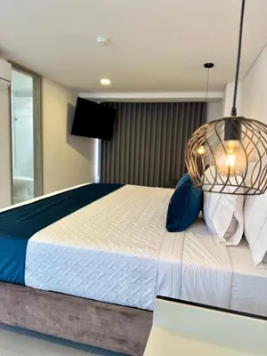 a bedroom with a large bed with blue pillows at Hotel ECO 44 in Medellín