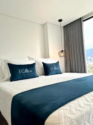 a bedroom with a bed with blue and white pillows at Hotel ECO 44 in Medellín