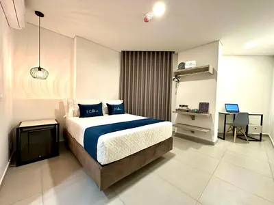 a bedroom with a bed and a desk with a laptop at Hotel ECO 44 in Medellín