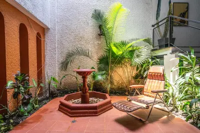 a patio with a fountain and a chair and plants at Colonial Villa in Laureles, Unique&Special House in Medellín