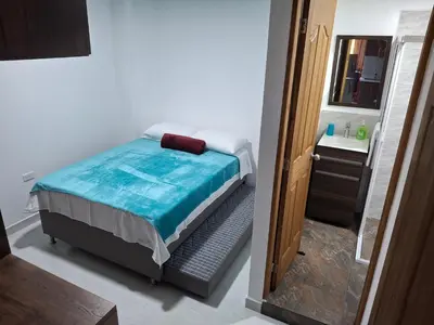 a small bedroom with a bed and a bathroom at Acogedor Apartamento de 3 dormitorios con baños privados - Guatapé Antioquia in Guatapé