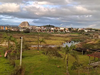 a field with a town in the background with a river at Acogedor Apartamento de 3 dormitorios con baños privados - Guatapé Antioquia in Guatapé