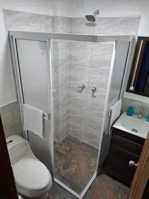 a bathroom with a shower with a toilet and a sink at Acogedor Apartamento de 3 dormitorios con baños privados - Guatapé Antioquia in Guatapé
