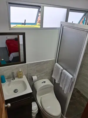 a bathroom with a toilet and a sink and a mirror at Acogedor Apartamento de 3 dormitorios con baños privados - Guatapé Antioquia in Guatapé