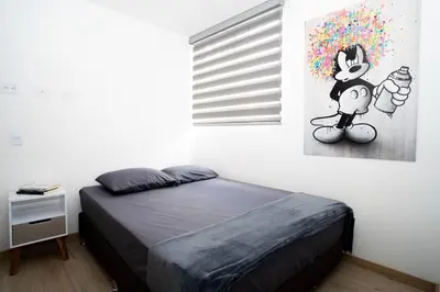 a bedroom with a bed and a painting of a mickey mouse at Amazing cozy & new flat 3 bedrooms in Medellin best location in Medellín