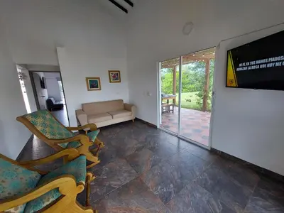 a living room with a couch and a flat screen tv at Finca Ecológica Sopetran in Sopetran