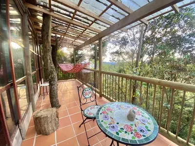 a porch with a table and chairs and a hammock at Refugio Santa Elena in Santa Elena