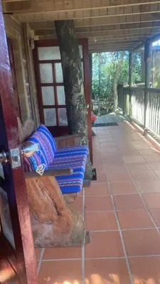 a porch with a bench with pillows on it at Refugio Santa Elena in Santa Elena