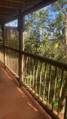 a wooden railing on a porch with trees in the background at Refugio Santa Elena in Santa Elena