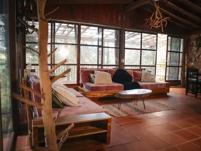 a woman sitting on a couch in a room with windows at Refugio Santa Elena in Santa Elena