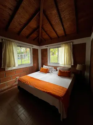 a bedroom with a large bed with two windows at Yarumito Finca Hotel Cabaña Narciso in Barbosa