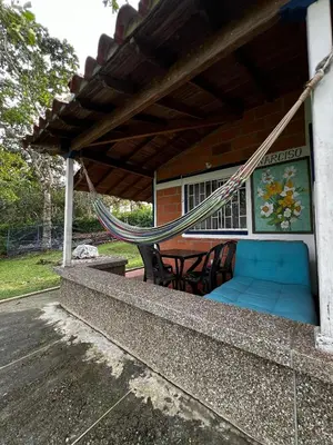 a porch with a hammock and a table and chairs at Yarumito Finca Hotel Cabaña Narciso in Barbosa