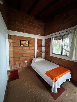 a bedroom with a bed in a brick wall at Yarumito Finca Hotel Cabaña Narciso in Barbosa