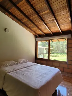 a bedroom with a bed and a large window at La Pascana Ecolodge frente al parque Arví Entorno natural excepcional, reserva natural, áreas protegidas, conexión con la naturaleza y avistamiento de aves a 3km del metrocable Guarne in Guarne