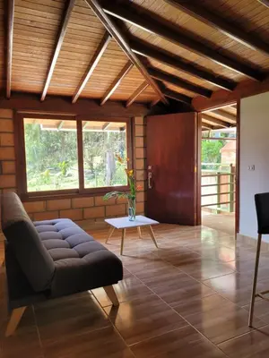 a living room with a couch and a table at La Pascana Ecolodge frente al parque Arví Entorno natural excepcional, reserva natural, áreas protegidas, conexión con la naturaleza y avistamiento de aves a 3km del metrocable Guarne in Guarne