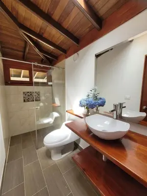 a bathroom with a sink and a toilet and a mirror at La Pascana Ecolodge frente al parque Arví Entorno natural excepcional, reserva natural, áreas protegidas, conexión con la naturaleza y avistamiento de aves a 3km del metrocable Guarne in Guarne