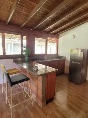a kitchen with a counter and a refrigerator at La Pascana Ecolodge frente al parque Arví Entorno natural excepcional, reserva natural, áreas protegidas, conexión con la naturaleza y avistamiento de aves a 3km del metrocable Guarne in Guarne