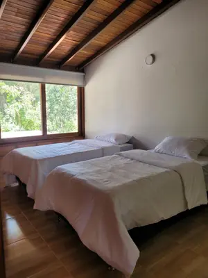 two beds in a room with two windows at La Pascana Ecolodge frente al parque Arví Entorno natural excepcional, reserva natural, áreas protegidas, conexión con la naturaleza y avistamiento de aves a 3km del metrocable Guarne in Guarne