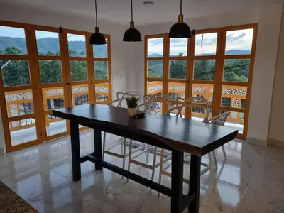 a dining room with a table and chairs and windows at 1Cálido y Amarillo in Jericó