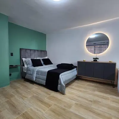 a bedroom with a large bed and a mirror at Loft with bathtub in Laureles in Medellín