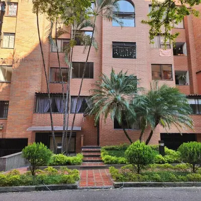 a brick building with palm trees in front of it at Loft with bathtub in Laureles in Medellín