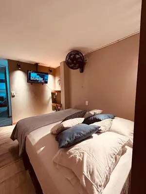 a bedroom with a bed with pillows and a tv on the wall at Renacer, Poblado Manila in Medellín