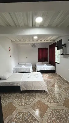 a room with two beds and a television in it at Alojamiento Doradal Antioquía, en el santorini colombiano, la aldea in Doradal