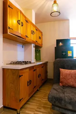 a kitchen with wooden cabinets and a couch in a room at Suite Encanto in Jericó