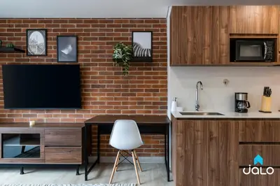 a kitchen with a tv and a brick wall at Kyux Studios by Jalo - Laureles in Medellín