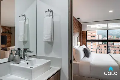 a bathroom with a sink and a bed and a window at Kyux Studios by Jalo - Laureles in Medellín