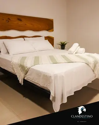 a bedroom with a large bed with white sheets at Clandestino - Hotel Boutique in La Dorada